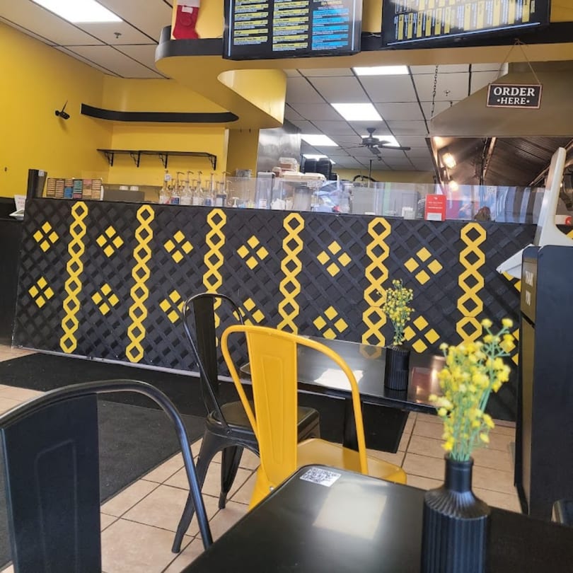 Interior of The Melted Madness with yellow and black decor, a service counter, and seating.